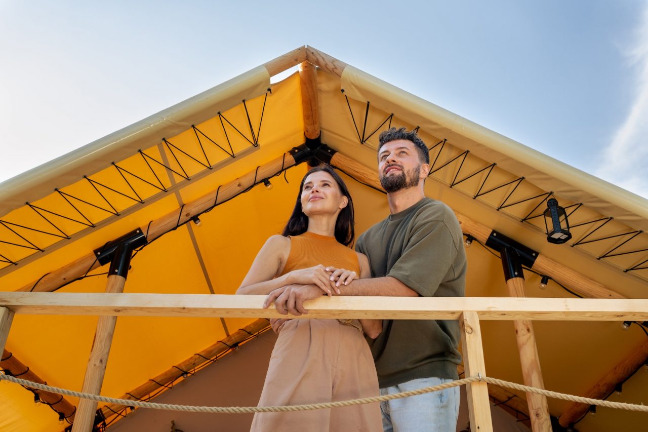 Couple standing near a glamping house during a hill getaway